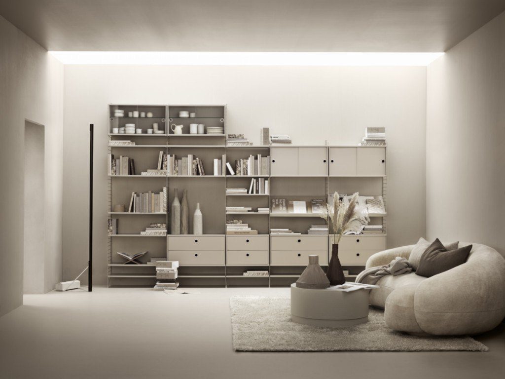 Modernes String Furniture Regal mit Büchern und Deko-Objekten im stilvollen Wohnzimmer.