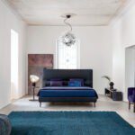 Modernes Twils De Light Bett mit gepolstertem Kopfteil und eleganten Holzbeinen.